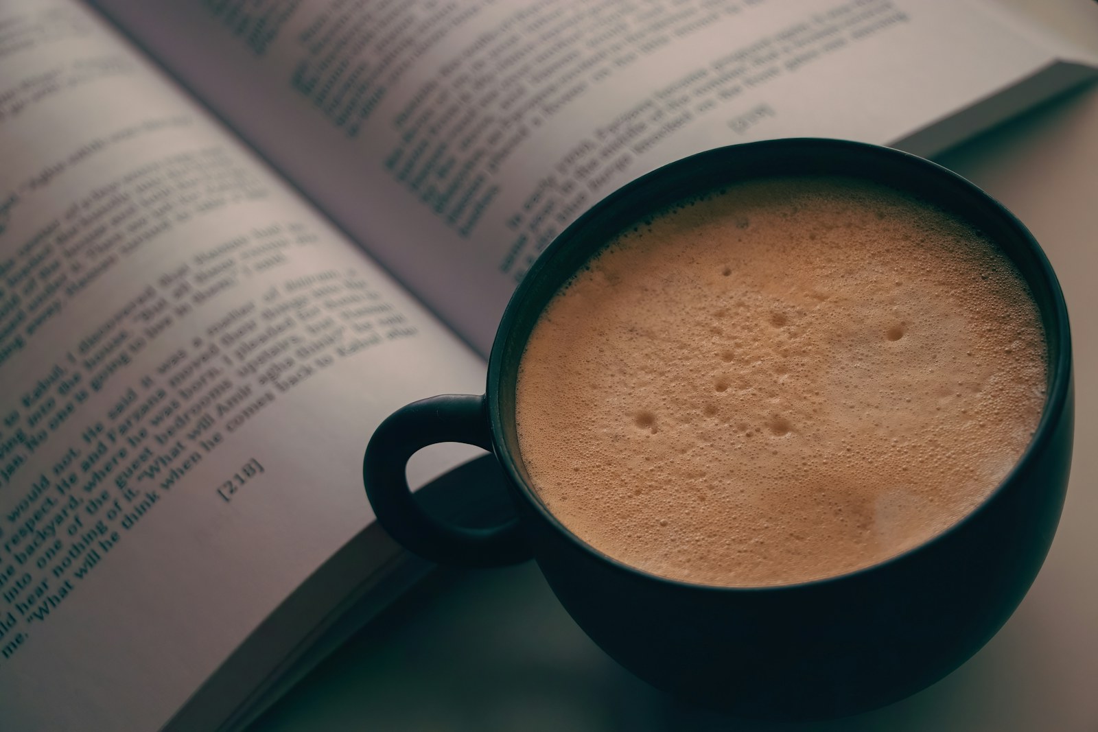 Un libro abierto junto a un café, fotografía ilustrativa